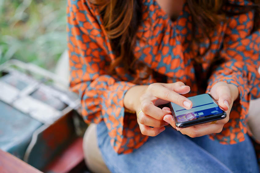 A Woman Holding a Smartphone and Browsing on Facebook A Woman Holding a Smartphone and Browsing on Facebook