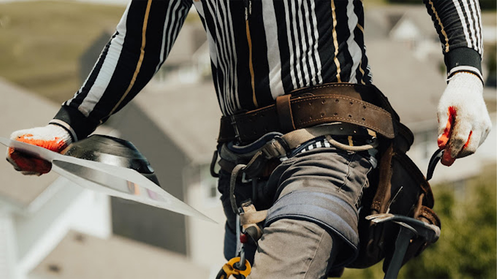 roofer wearing harness and holding a cover